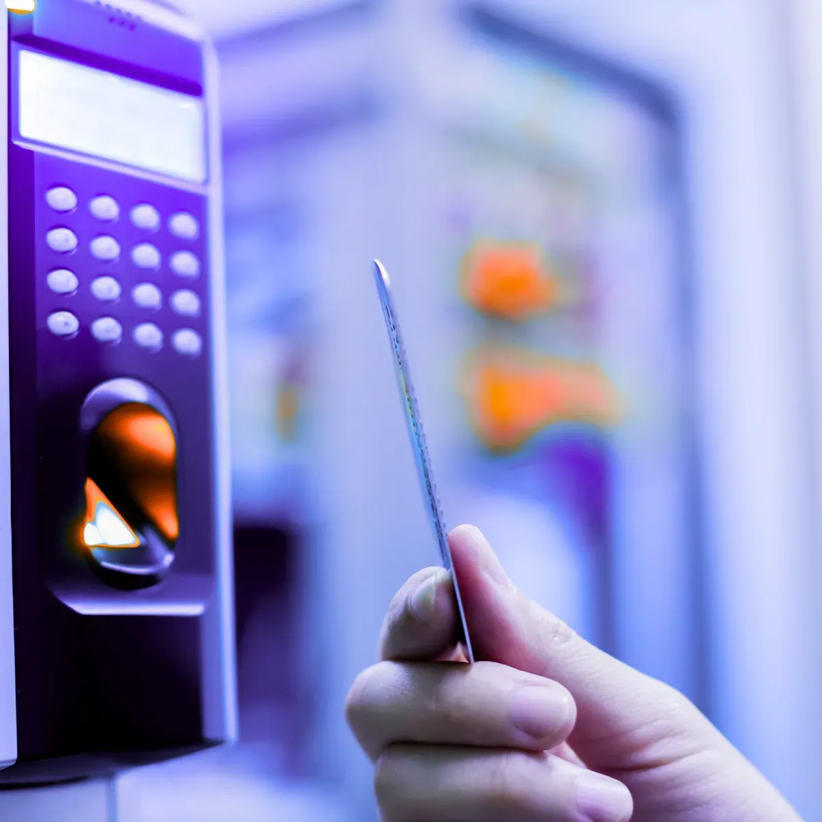Person holding an access card in front of an electronic RFID reader