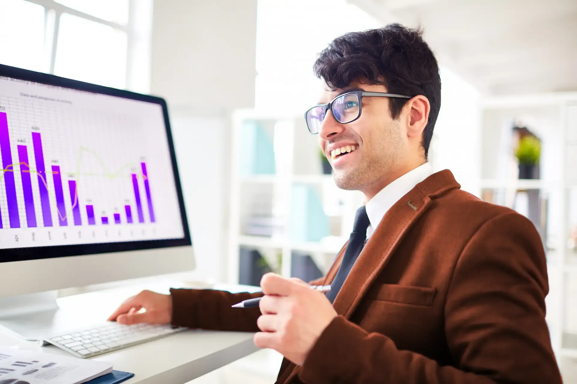 A broker dealer smiling at his desktop showing a graph.