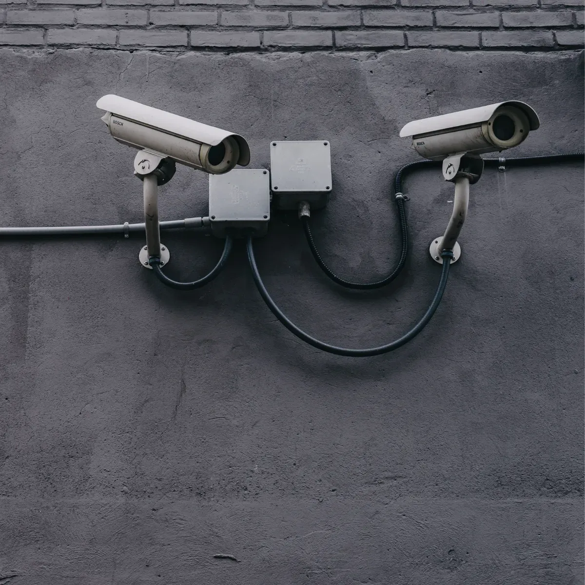 Two security cameras mounted on a gray wall