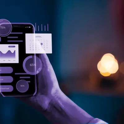 Hand holding smartphone with floating purple digital graphs and data.