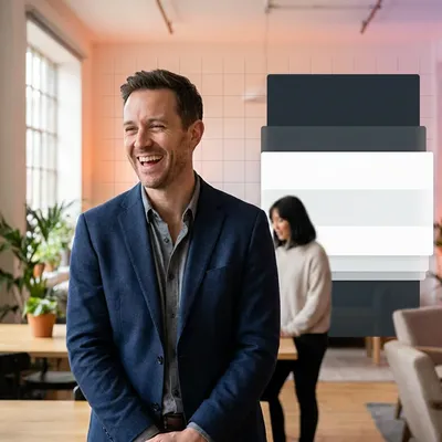 Smiling man in a blue blazer talking to a colleague in a modern office.