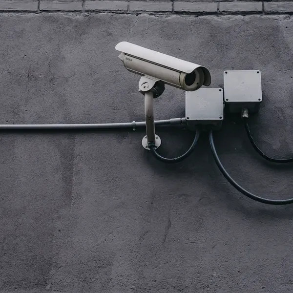 Two white security cameras mounted on a dark grey concrete wall.