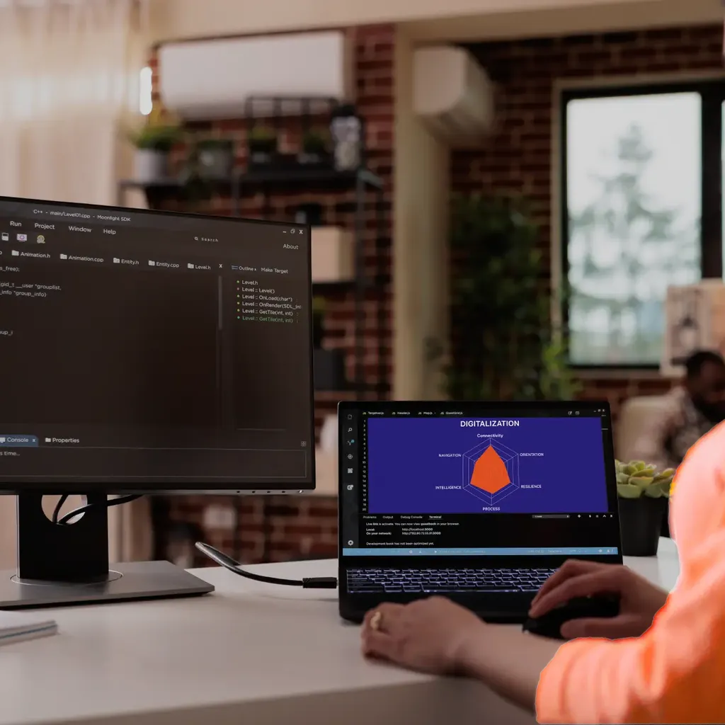 Eine Entwicklerin arbeitet an einem Laptop und einem Monitor mit Code.