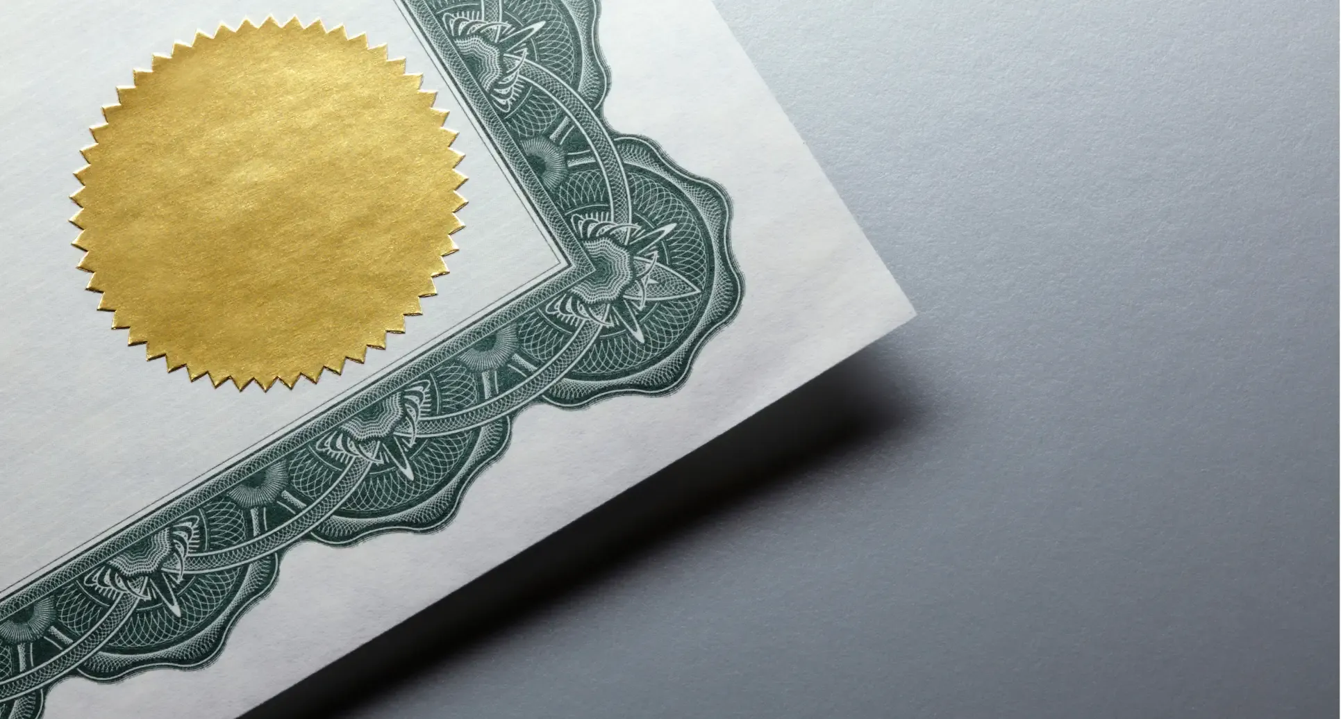 Ecke einer Urkunde mit Goldsiegel und grünem Zierrand.