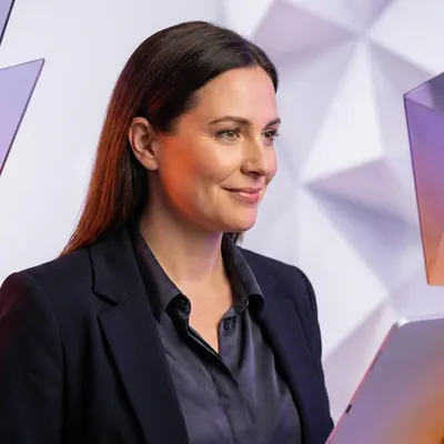 Smiling businesswoman holding a tablet against a modern, abstract geometric background.
