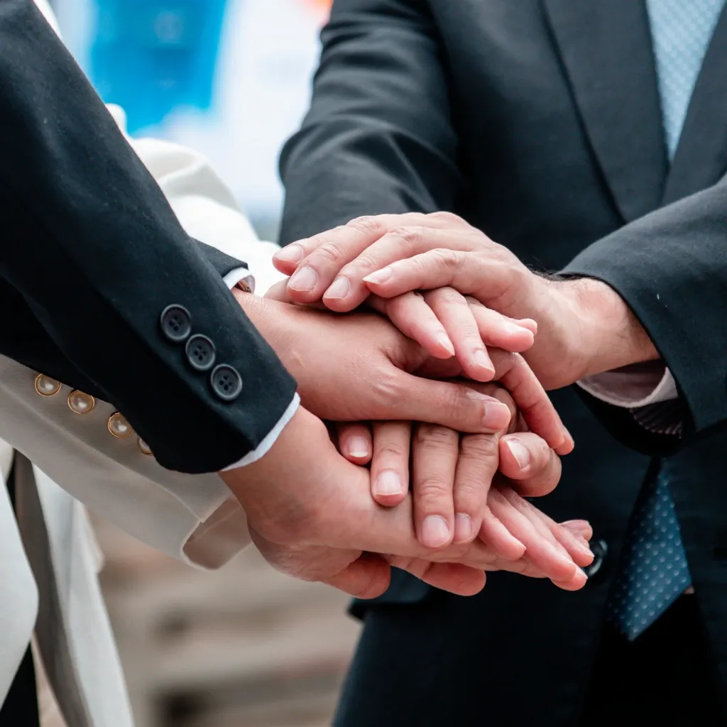 A team placing their hands on top of each other in an office setting