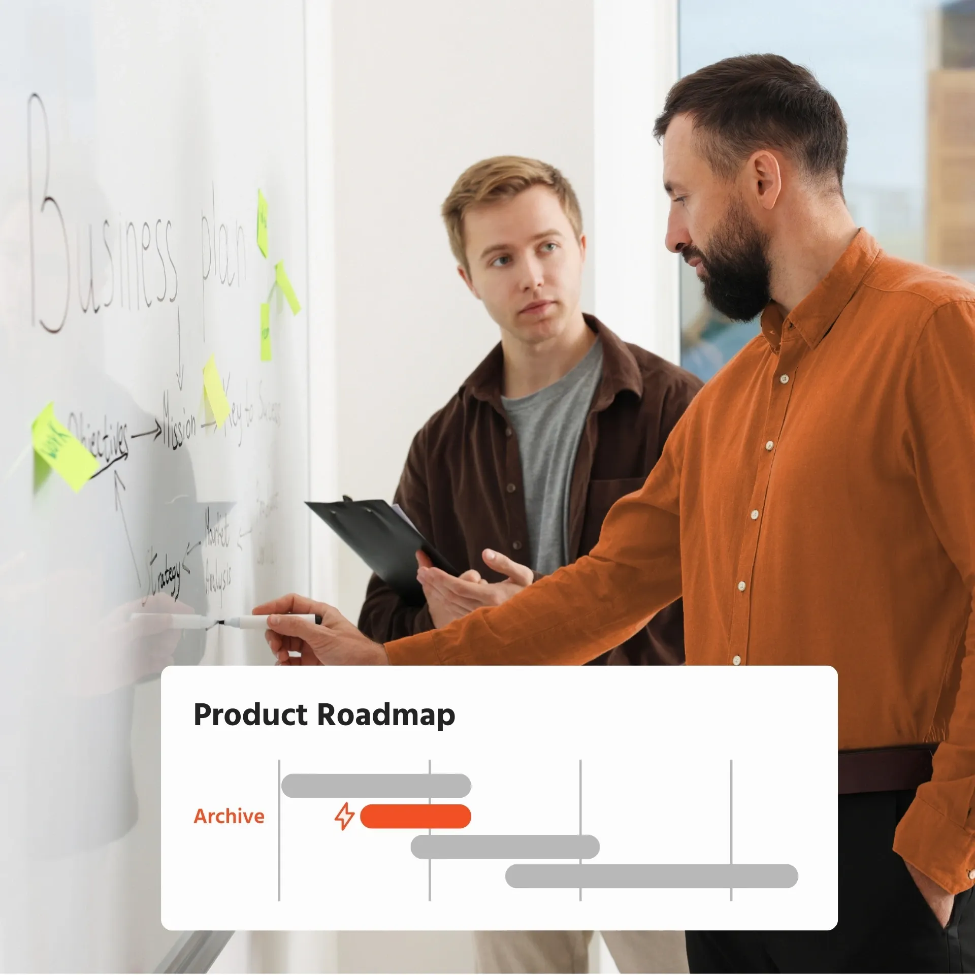 Two men collaborate on a business plan at a whiteboard.