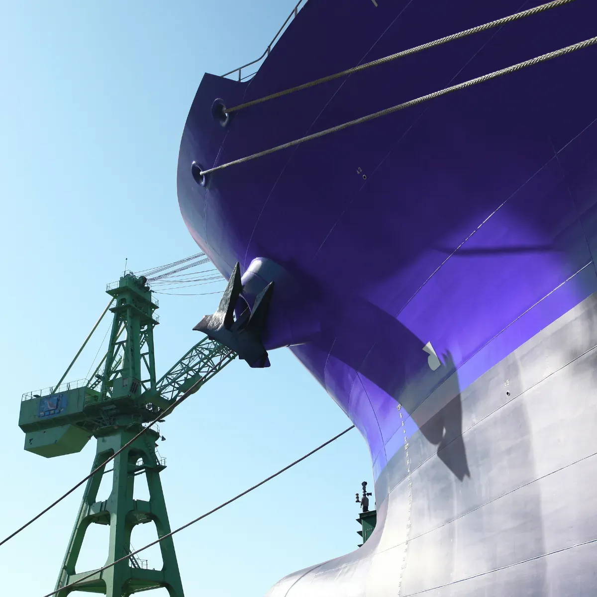 Large ship hull in a shipyard with a crane in the background