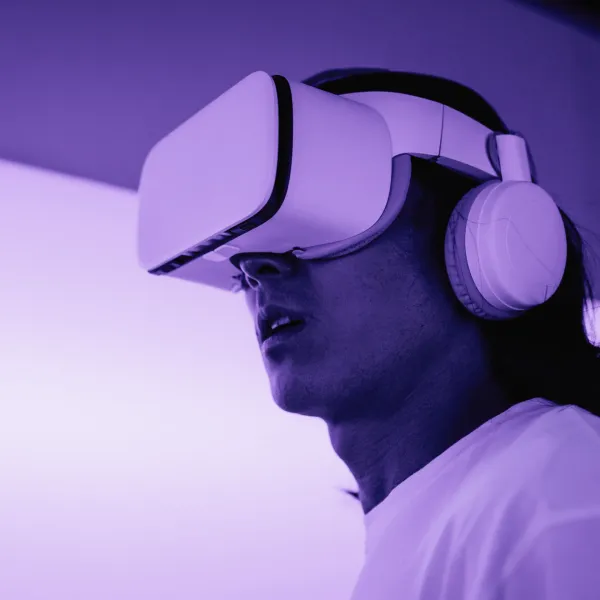 Person wearing a VR headset and headphones in purple light.