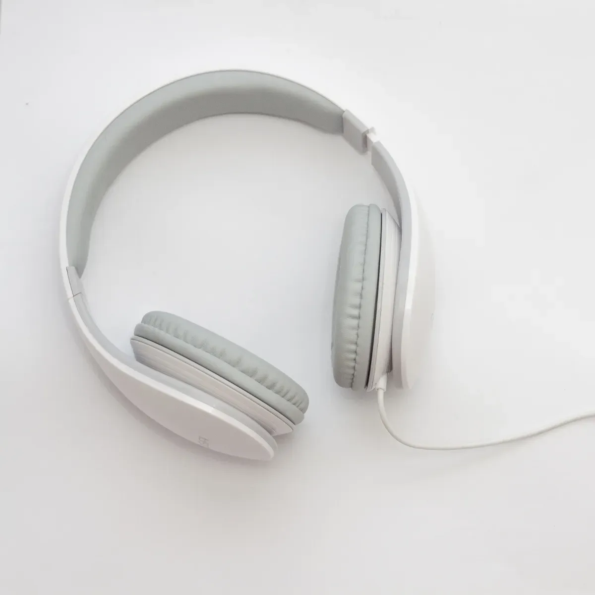 White over-ear headphones lying on a bright background